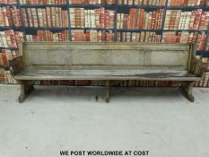 A substantial vintage oak pew with panelled back and bowed stretchers of peg jointed construction,
