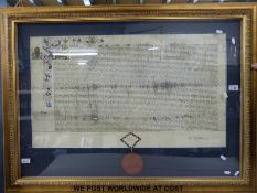 A framed document in latin script with gilt illumination and wax seal (width 84cm)