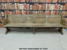 A substantial vintage oak pew with panelled back and bowed stretchers of peg jointed construction,