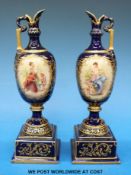 A pair of Vienna porcelain ewers with hand-painted decoration on a white and blue ground (21cm