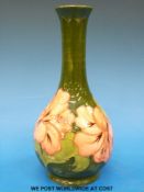 A Moorcroft pottery vase in Hibiscus pattern on a green ground (height 22cm)
