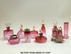 A collection of cranberry glass to include seven faceted scent bottles and powder pots,