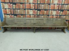 A substantial vintage oak pew with panelled back and bowed stretchers of peg jointed construction,