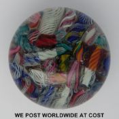 A scrambled glass paperweight with various multicoloured latticino tubes.