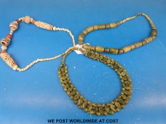 Two green hardstone necklaces together with a carved ivory necklace