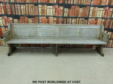 A substantial vintage oak pew with panelled back and bowed stretchers of peg jointed construction,