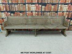 A substantial vintage oak pew with panelled back and bowed stretchers of peg jointed construction,