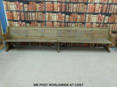 A substantial vintage oak pew with panelled back and bowed stretchers of peg jointed construction,