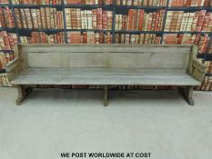 A substantial vintage oak pew with panelled back and bowed stretchers of peg jointed construction,