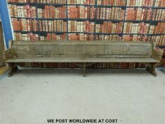A substantial vintage oak pew with panelled back and bowed stretchers of peg jointed construction,