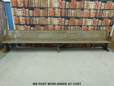 A substantial vintage oak pew with panelled back and bowed stretchers of peg jointed construction,