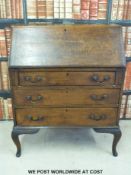 An oak drop leaf table and an oak bureau raised on cabriole legs