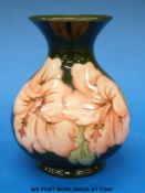 A Moorcroft pottery vase in Hibiscus pattern on a green ground (height 13cm)
