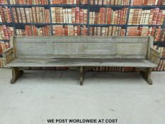 A substantial vintage oak pew with panelled back and bowed stretchers of peg jointed construction,