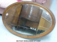 An oval oak framed bevelled glass mirror