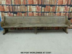A substantial vintage oak pew with panelled back and bowed stretchers of peg jointed construction,