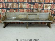 A substantial vintage oak pew with panelled back and bowed stretchers of peg jointed construction,