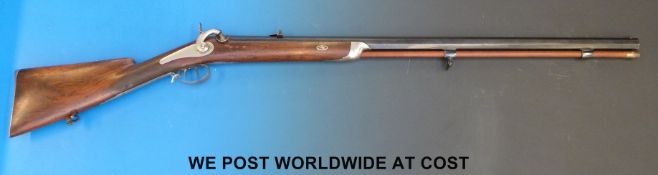 A single barrelled muzzle loading hammer action rifle with white metal inlay, carved stock,