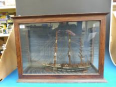 A model sailing ship in oak glazed case