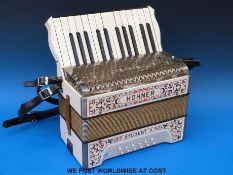 A Hohner Student II 12 bass piano accordion in ivory finish with red blue and gold decoration,