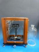 A Baird & Tatlock laboratory balance scale in case and a glass cloche