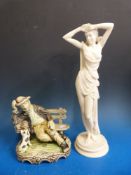 An alabaster statue of a lady and a model of a man on a bench with a dog