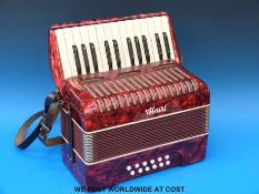 A cased Alwari 12 bass piano accordion in red pearloid finish.