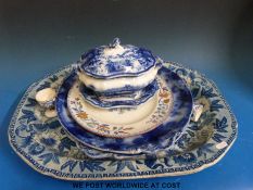 A large blue and white meat dish featuring a man riding a zebra together with other blue and white