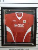 An autographed Bristol City football shirt signed by 15 players, framed and glazed.