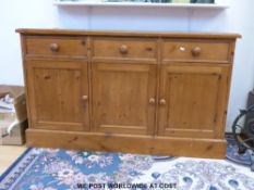 A pine three drawer sideboard with cupboards below (W137 x D44 x H82cm)