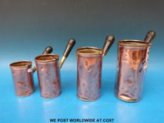 A set of four graduated copper measures with brass and wooden handles