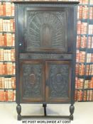 A double height corner cupboard with single carved door to top,