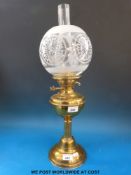 A brass oil lamp with etched globe type shade
