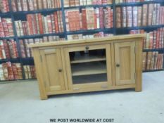 A modern light oak television stand with glazed fall flap door (W110 x H59cm)