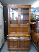 An Ercol dresser/ secretaire unit with glazed cupboard above drop flap to top and two drawers above