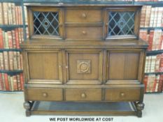 An oak sideboard with leaded glass cupboards to top section (W136 x D45 x H127cm)