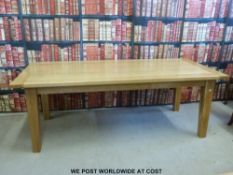 A modern light oak table raised on square tapering legs (L210 x W90 x H76cm)