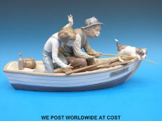 A Lladro figural group of a man, child and puppy fishing from a rowing boat (19cm tall,