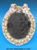 A German figural oval mirror with applied flower decoration and with easel back,