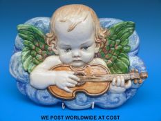 A continental ceramic plaque of a putti playing a guitar (length 27cm)