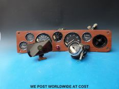 A c1970's TR car dashboard and gauges together with a rear view mirror clock