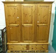A three door pine wardrobe with drawers below (W176 x D61 x H197cm)