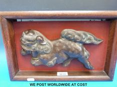 A Chinese bronze model of a Foo Dog mounted in a wooden frame