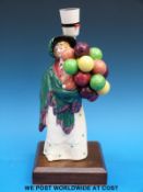 A Royal Doulton figure The Balloon Seller mounted on a wooden plinth with a light fitting