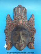 A Balinese wall hanging in the form of a woman's face wearing a head dress, c1930,