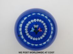 Caithness paperweight featuring three stylized flowers surrounded by a ring of white canes on a
