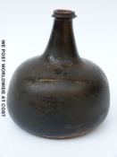 A 17th/18thC green glass onion bottle with remnants of iridescent and gilt colouring to the base