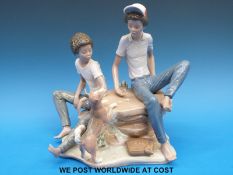 A Lladro figural group of teenagers playing dice with pet dog in attendance (19cm tall)