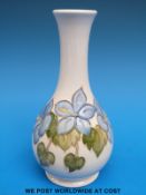 A Moorcroft bud vase decorated with blue hepaticas on a cream ground (15.