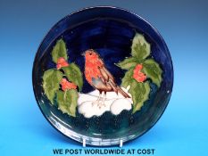 A Moorcroft Christmas plate featuring a robin surrounded by holly (22cm wide)